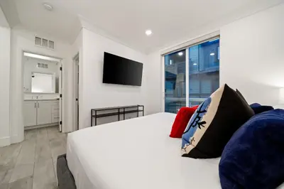 a bedroom with a white bed and a flat screen tv at Bayside Delight Just Steps to Water in San Diego