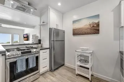 a kitchen with a stainless steel refrigerator and white cabinets at Ocean VIEWS! Steps from Victoria Beach, Lux Design in Laguna Beach