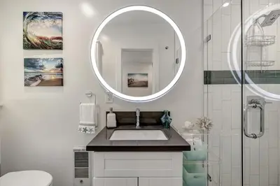 a white bathroom with a sink and a mirror at Ocean VIEWS! Steps from Victoria Beach, Lux Design in Laguna Beach