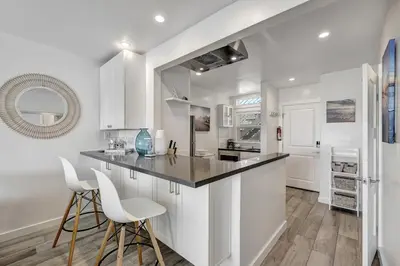 a kitchen with white cabinets and a counter with stools at Ocean VIEWS! Steps from Victoria Beach, Lux Design in Laguna Beach