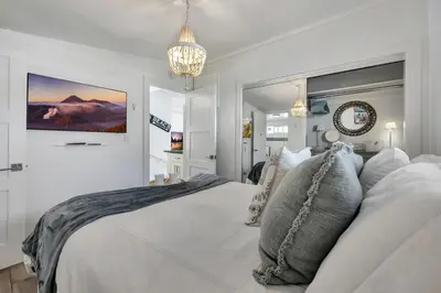 a bedroom with a large white bed and a chandelier at Ocean Views! Detached Villa by Victoria Beach in Laguna Beach