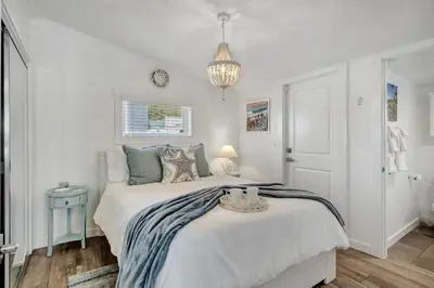 a white bedroom with a bed and a chandelier at Ocean Views! Detached Villa by Victoria Beach in Laguna Beach