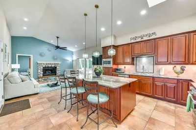 a kitchen with wooden cabinets and a bar with stools at 13 Mi to Downtown San Diego Quiet Home with Spa! in Chula Vista