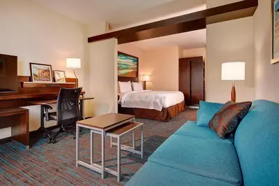 a hotel room with a blue couch and a bed at Fairfield Inn & Suites by Marriott San Diego Carlsbad in Carlsbad