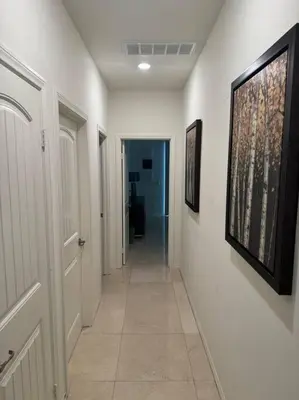 a hallway of a house with white walls and paintings on the walls at Luxury 1200 sqft 1bdrm retreat with den in Menifee
