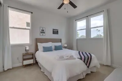 a white bedroom with a large bed with blue pillows at Rooftop Patio Hot Tub AC Beach & Bay Views in San Diego