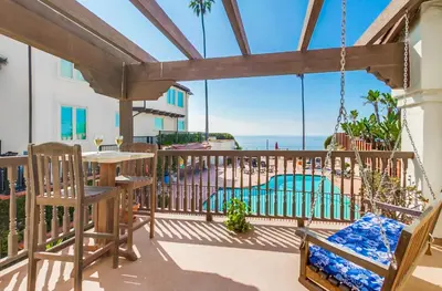 a porch with a swing and a swimming pool at Ocean Views Moonlight Beach Ocean Deck Pool Hot Tub in Encinitas