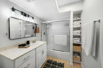 a bathroom with a shower and a sink and a mirror at Beacons Beach Cottage in Encinitas