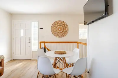 a dining room with a table and white chairs at Beacons Beach Cottage in Encinitas