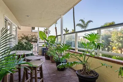 a balcony with plants and tables and windows at Oceanview Townhome Just Steps from Iconic Windansea Beach in San Diego
