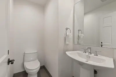 a white bathroom with a toilet and a sink at Oceanview Townhome Just Steps from Iconic Windansea Beach in San Diego