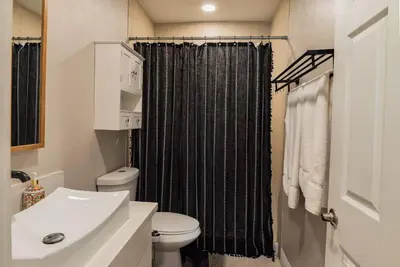 a bathroom with a black shower curtain and a toilet at SDSU and Downtown Less Than 10 Min, Game Room, and Fire Pit in La Mesa