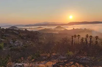 a sunset over a mountain range with the sun in the sky at Gentle and Cozy Comfort in an Off-Grid Retreat in Fallbrook