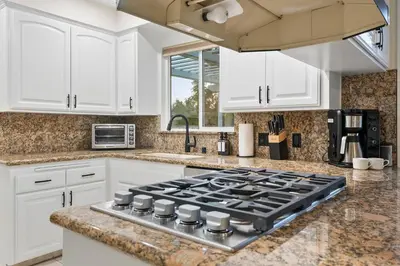 a kitchen with white cabinets and a stove top oven at Hills Hideaway by CoastVH - Luxury Midtown 3br in San Diego