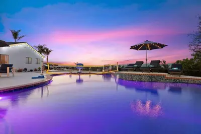 a large swimming pool with chairs and an umbrella at Immaculate 5BR Micro Resort with Heated Pool & Spa in San Diego