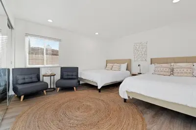 a bedroom with two beds and two chairs and a rug at Immaculate 5BR Micro Resort with Heated Pool & Spa in San Diego