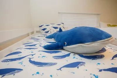 a blue stuffed whale laying on a bed at 2 private masters, new beds & furniture, sleeps 12 in San Diego