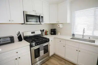 a kitchen with white cabinets and a stove top oven at 2 private masters, new beds & furniture, sleeps 12 in San Diego