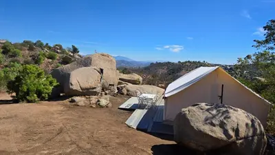 a small white building with rocks in the dirt at A Cozy Sunrise Glamping Escape with Panoramic View in Fallbrook