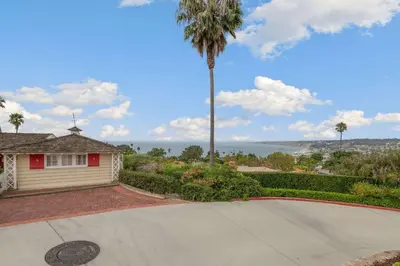 a house with a palm tree next to a driveway at The Porter House - Sweeping Ocean Views - La Jolla in San Diego