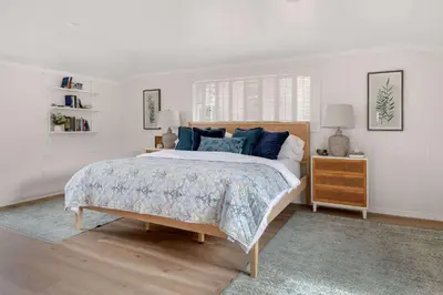 a white bedroom with a large bed with blue pillows at The Porter House - Sweeping Ocean Views - La Jolla in San Diego