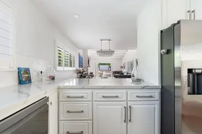 a kitchen with white cabinets and a black refrigerator at Luxury La Jolla Home with Jacuzzi in San Diego