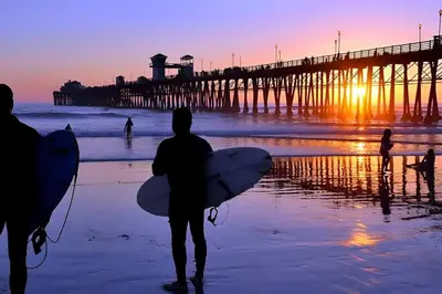 a group of people walking on the beach with surfboards at Majestic Lux Home with Heated Pool and Spa! in San Diego