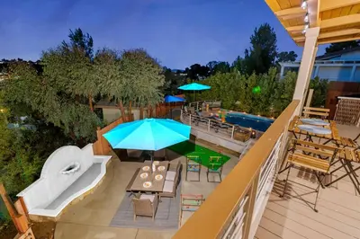 an outdoor patio with a table and umbrella and a pool at Majestic 5BR Villa with Guesthouse, Pool & Spa in Poway