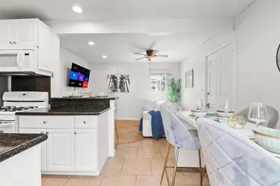 a kitchen with white cabinets and a table with chairs at PB 1BR BOHO with Parking, AC, and Large Patio in San Diego