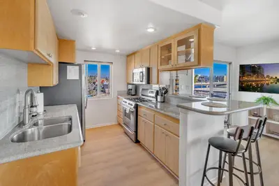 a kitchen with stainless steel appliances and wooden cabinets at Oceanside Harbor Getaway | Steps to Sand, Shops & Restaurants in Oceanside