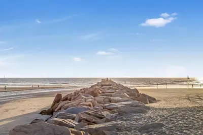 a rock wall on a beach near the ocean at Oceanside Harbor Getaway | Steps to Sand, Shops & Restaurants in Oceanside