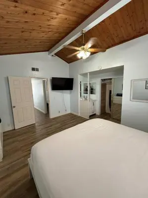 a bedroom with a white bed and a flat screen tv at Newport Beach Rendezvous in Newport Beach