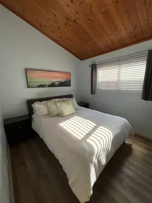 a bedroom with a white bed with a wooden ceiling at Newport Beach Rendezvous in Newport Beach