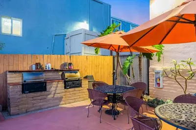 an outdoor patio with a grill and tables and umbrellas at 2 bed 2 bath penthouse condo with AC and Ocean Views in San Diego