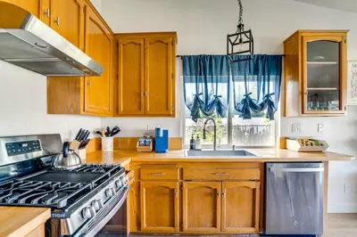 a kitchen with wooden cabinets and a stove top oven at Water-View Home with Hot Tub in Lake Elsinore! in Lake Elsinore