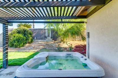 a hot tub in a backyard with a pergola at Water-View Home with Hot Tub in Lake Elsinore! in Lake Elsinore