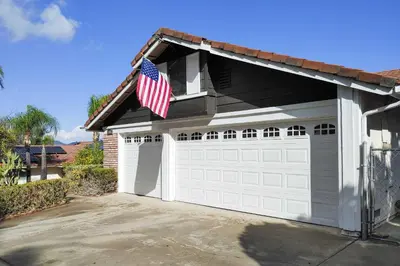 a house with a garage with an american flag on it at Water-View Home with Hot Tub in Lake Elsinore! in Lake Elsinore