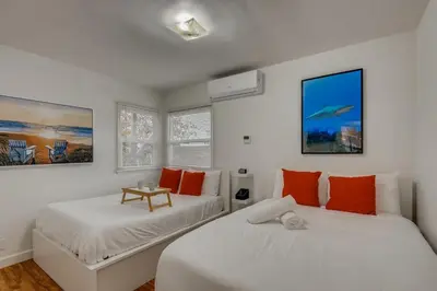 two beds in a room with white walls and orange pillows at Walk To Beach 2BR Top Location - AA in San Clemente
