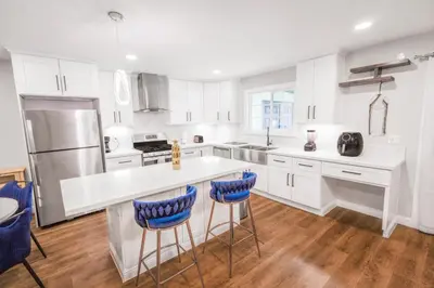 a kitchen with white cabinets and blue bar stools at Gillespie Drive 1063 Unit B by sdstay in Spring Valley