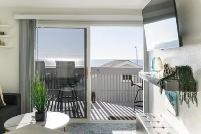 a living room with a balcony with a view of the ocean at Beachfront Bliss | Shining Sea Condo on The Strand w/ Ocean Views in Oceanside
