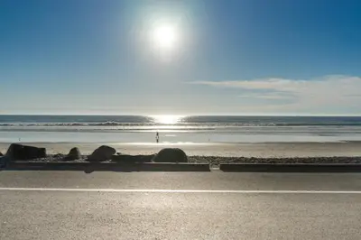 a beach with the sun rising over the ocean at Beachfront Bliss | Shining Sea Condo on The Strand w/ Ocean Views in Oceanside