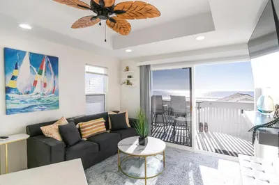 a living room with a couch and a ceiling fan at Beachfront Bliss | Shining Sea Condo on The Strand w/ Ocean Views in Oceanside