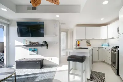 a kitchen with white cabinets and a counter with a stool at Beachfront Bliss | Shining Sea Condo on The Strand w/ Ocean Views in Oceanside