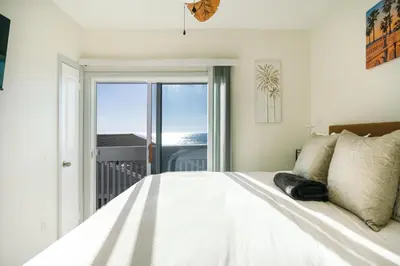 a bedroom with a large white bed with a window at Beachfront Bliss | Shining Sea Condo on The Strand w/ Ocean Views in Oceanside