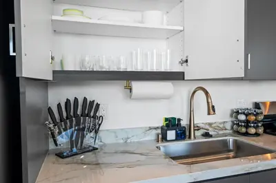 a kitchen with white cabinets and a sink and utensils at Modern 2 Bedroom King Bed EVCharger Pet-Friendly Balcony in San Diego