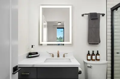 a white bathroom with a sink and a mirror at Modern 2 Bedroom King Bed EVCharger Pet-Friendly Balcony in San Diego