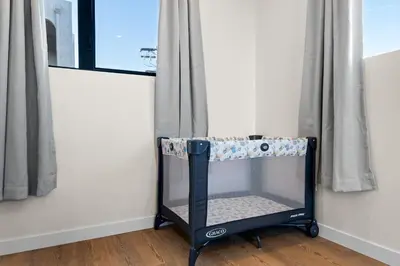a crib in a room next to a window at Modern 2 Bedroom King Bed EVCharger Pet-Friendly Balcony in San Diego