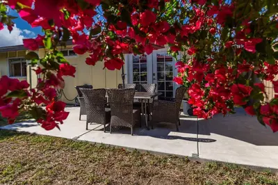 a table and chairs under a tree with red flowers at Giraffe House in Chula Vista