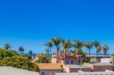 a house with palm trees and the ocean in the background at Lovely home with backyard oasis & great WiFi - walk to La Jolla Village, dogs OK in San Diego