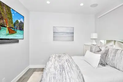 a white living room with a tv on a wall at Laguna Beach House in Laguna Beach